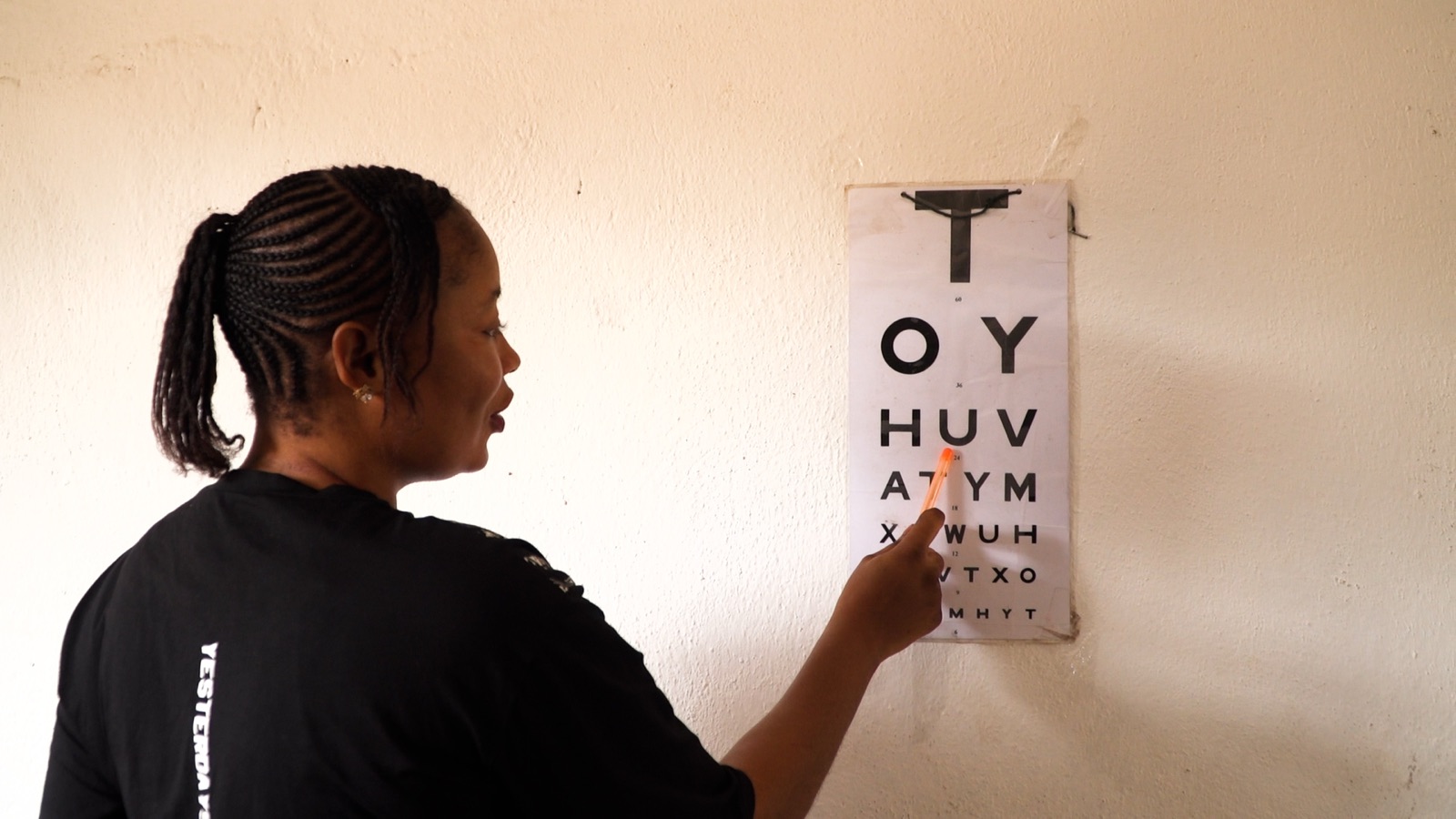 A health worker pointing to a letter on an eye chart